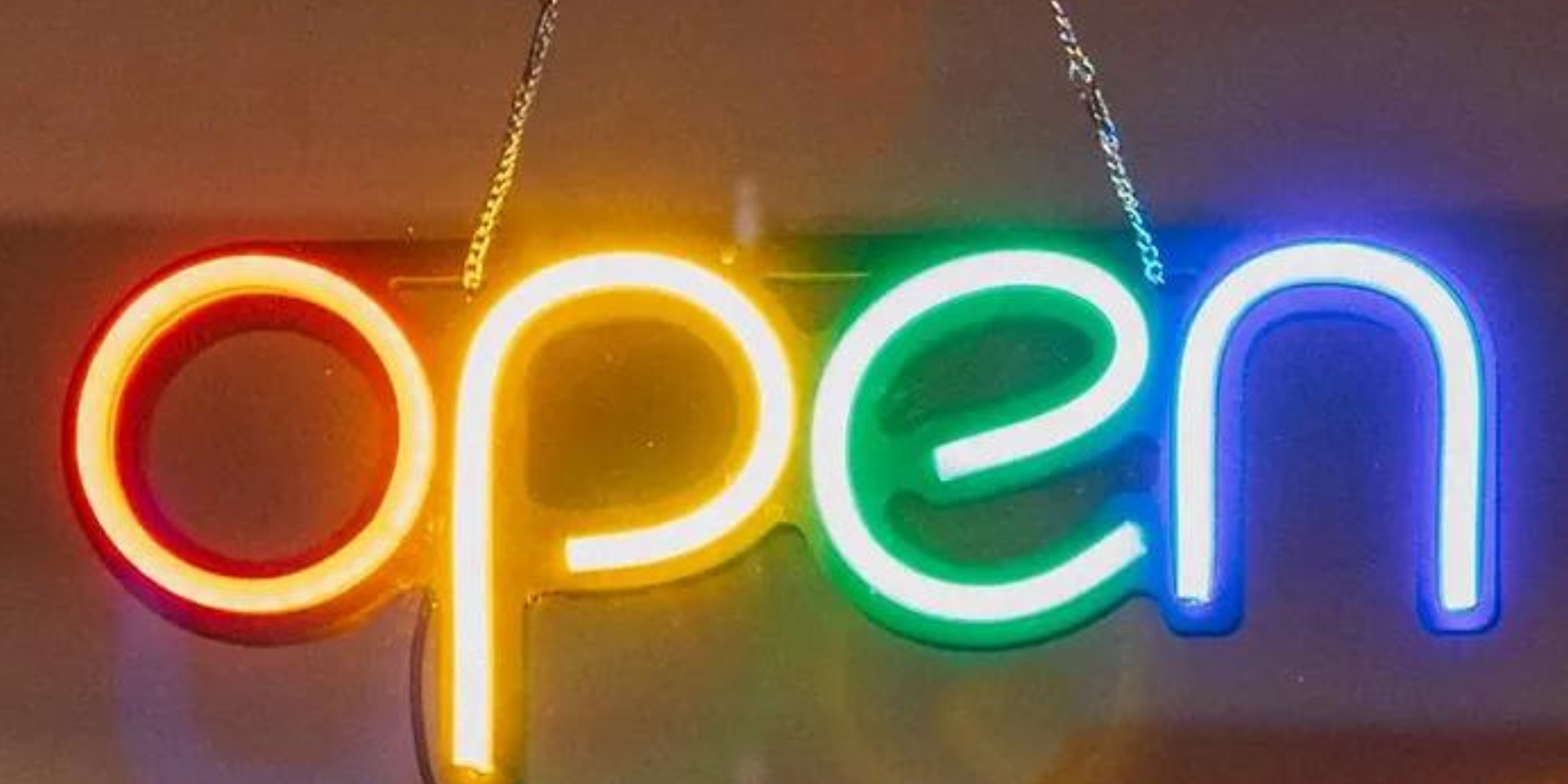 Neon 'Open' sign in bright, multicolored lights, symbolizing the welcoming atmosphere of the Lighthouse Psychiatry Open House event.