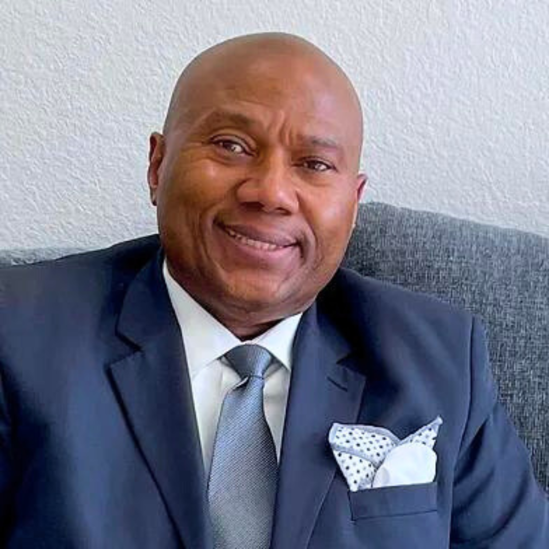 Smiling male therapist in a suit and tie seated on a couch.