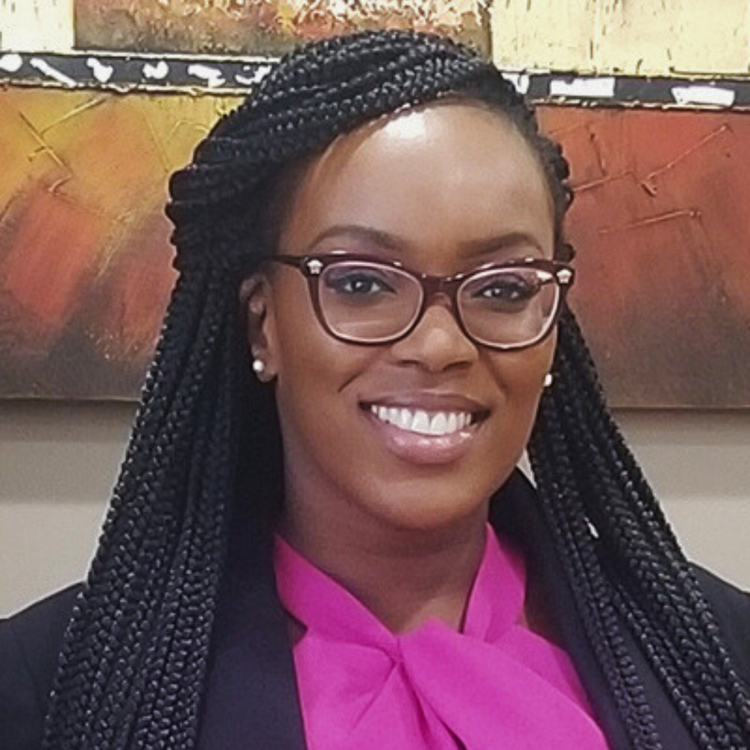 Smiling female therapist with braided hair and glasses in a professional setting.