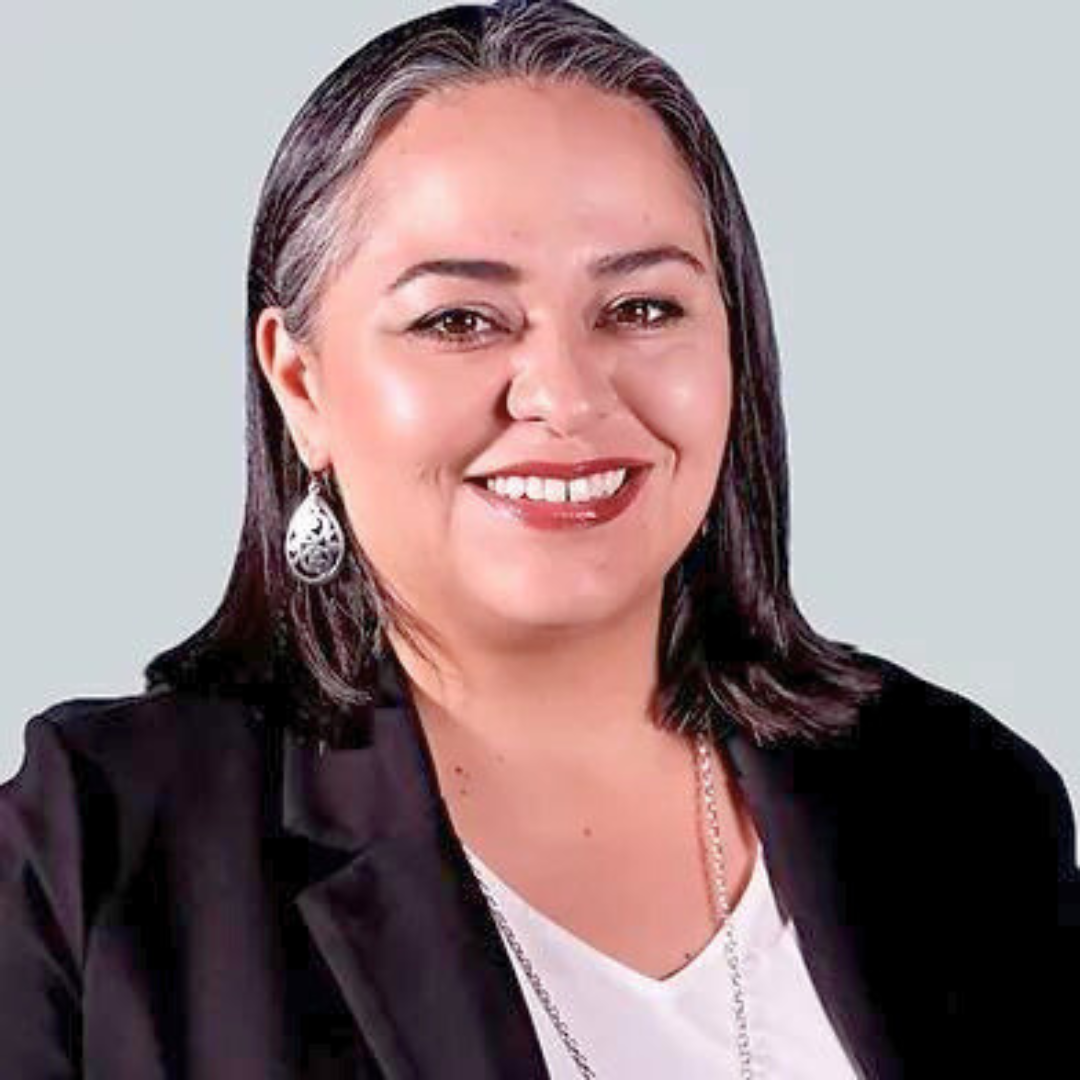 Smiling female therapist with dark hair wearing a black blazer and earrings.