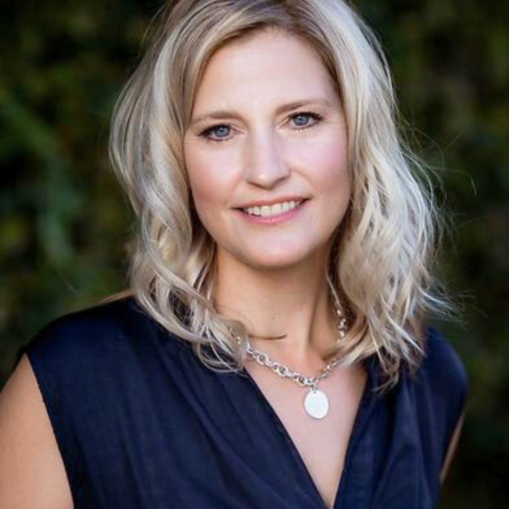 Smiling female therapist with blonde wavy hair wearing a navy top.