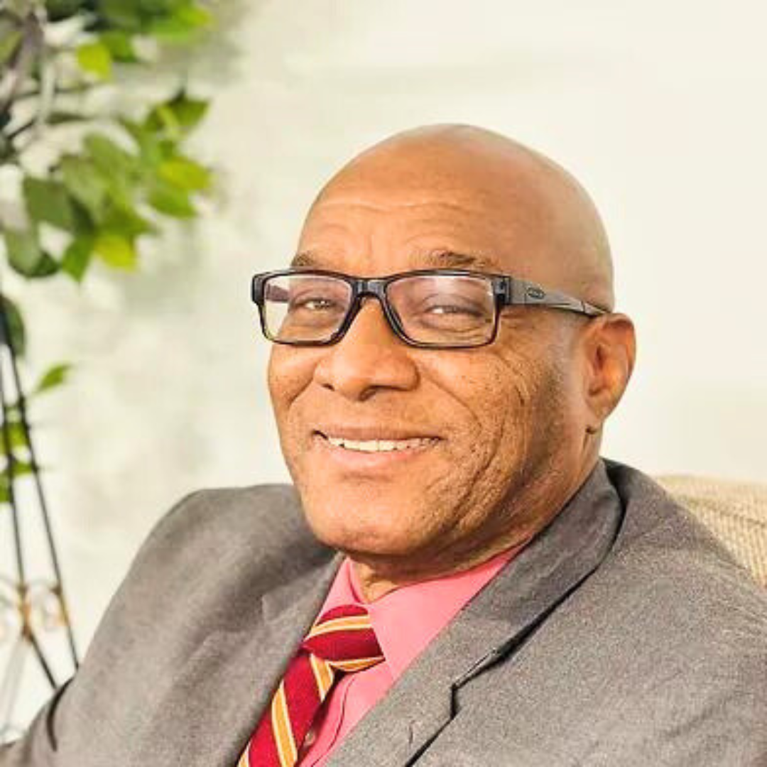 Smiling male therapist in a suit and glasses seated in a welcoming environment.