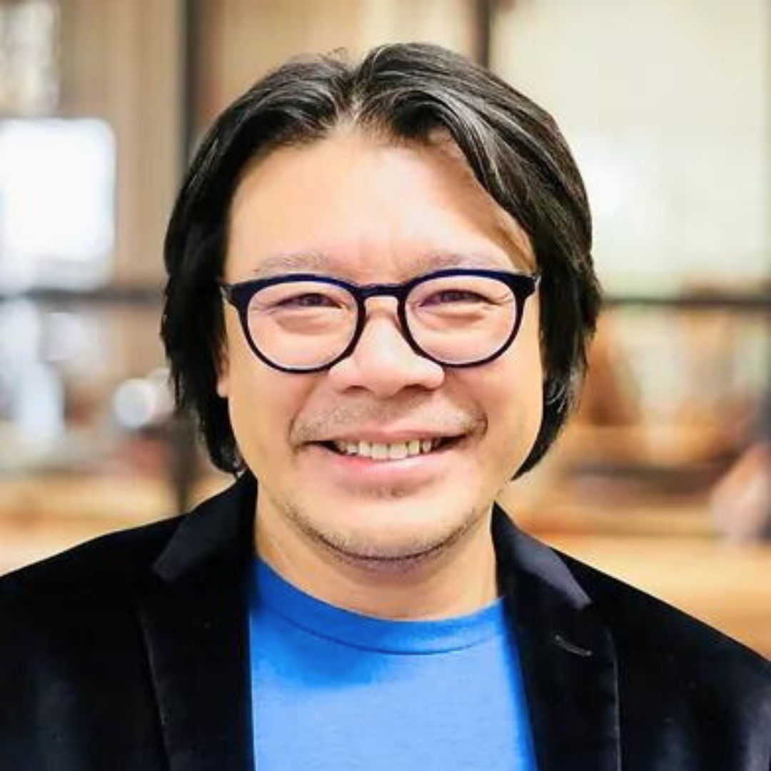 Smiling male therapist with glasses and dark hair in a casual indoor setting.