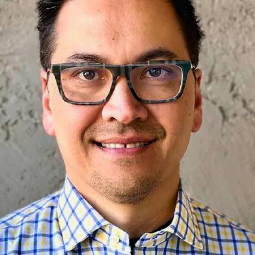 Smiling male therapist with glasses and a plaid shirt in a close-up portrai