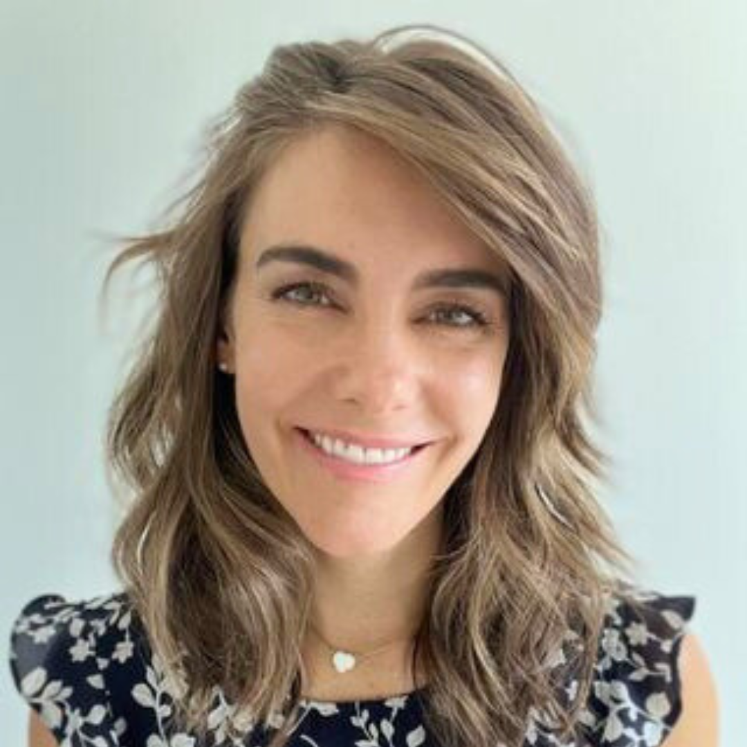 Smiling female therapist with wavy hair in a floral blouse.