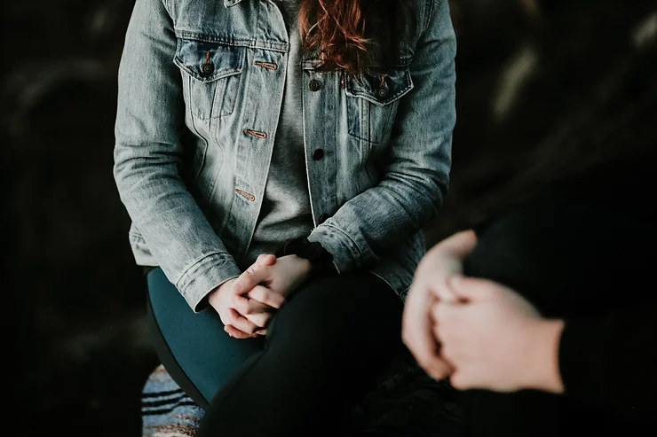 Close-up of two people in a therapy session, sitting with hands clasped, symbolizing support during combined TMS and talk therapy.