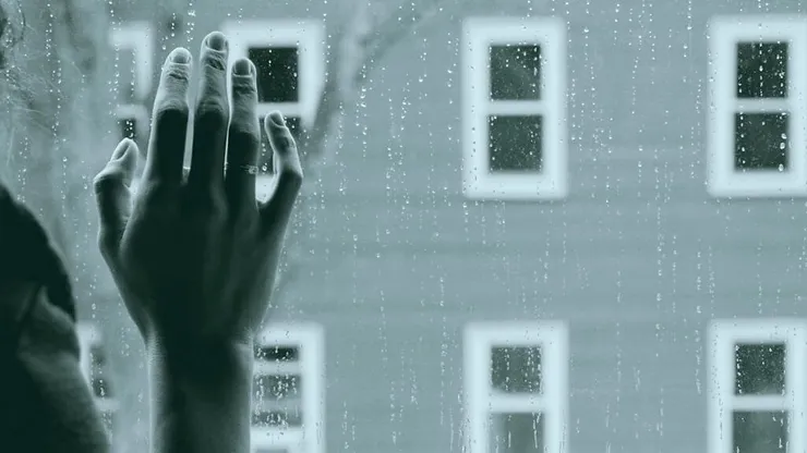 Hand pressed against a window during a rainy day, symbolizing the emotional challenges of depression.