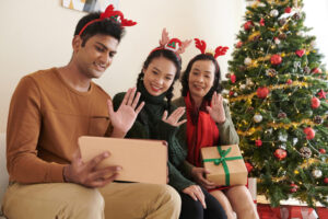 A family gathered on a couch, engaging with a tablet, with a beautifully decorated Christmas tree in the background