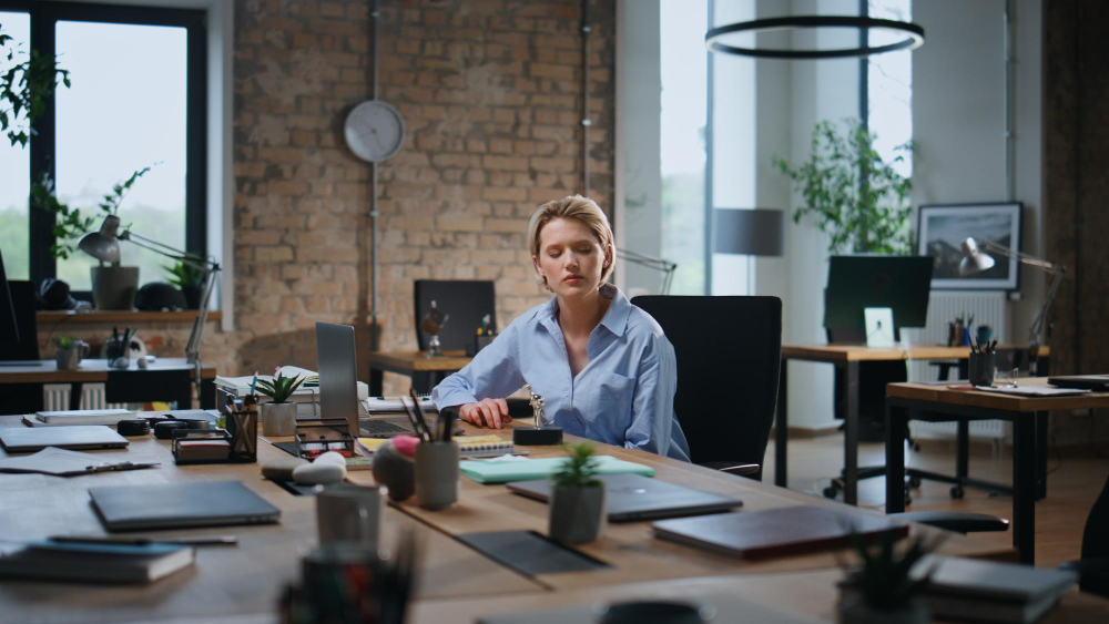 A woman at her desk in an office, engaged in her tasks with a computer and paperwork in front of her