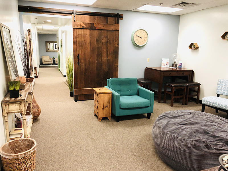 A cozy room featuring a comfortable couch, a stylish chair, and a classic wall clock, creating a welcoming atmosphere