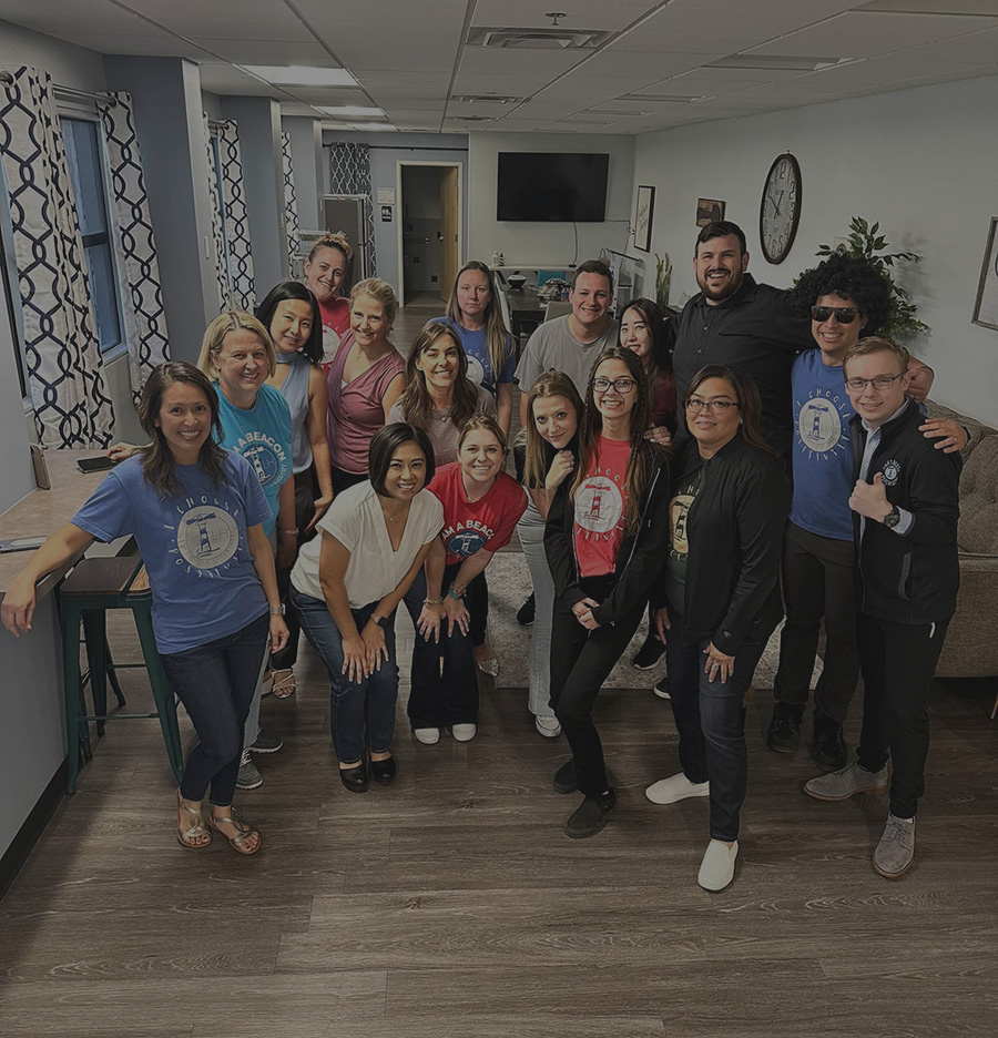 A cheerful group of individuals posing for a photograph in a contemporary office space, showcasing teamwork and camaraderie - Lighthouse Psychiatry A cheerful group of individuals posing for a photograph in a contemporary office space, showcasing teamwork and camaraderie