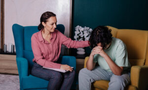 A woman engages in conversation with a man seated on a chair, showcasing a moment of dialogue and interaction