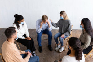 A group of people sitting in a circle, with one individual seeking help with mental health condition, engaged in conversation